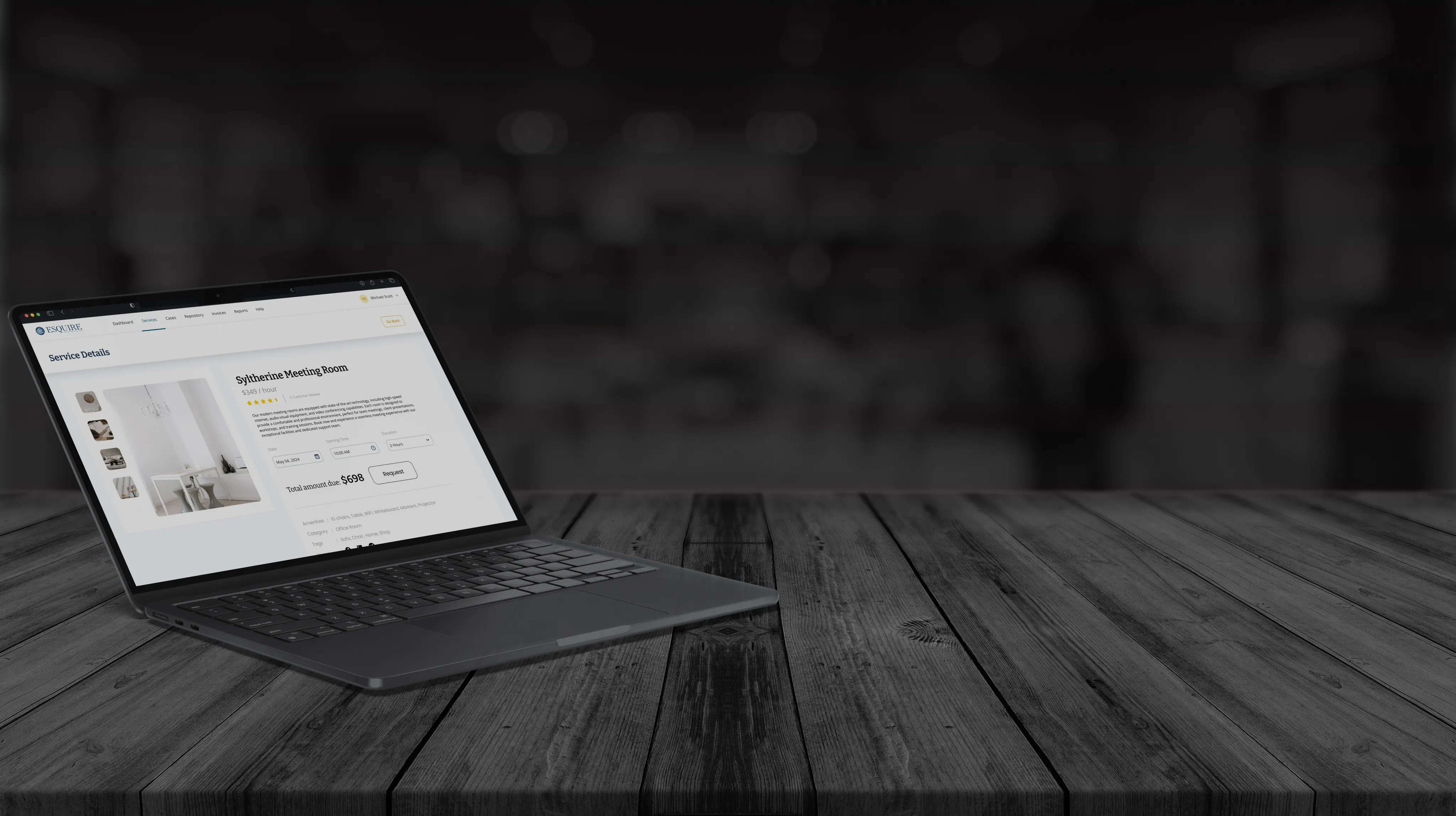 Laptop on a dark wooden table, showing an Esquire meeting room booking page