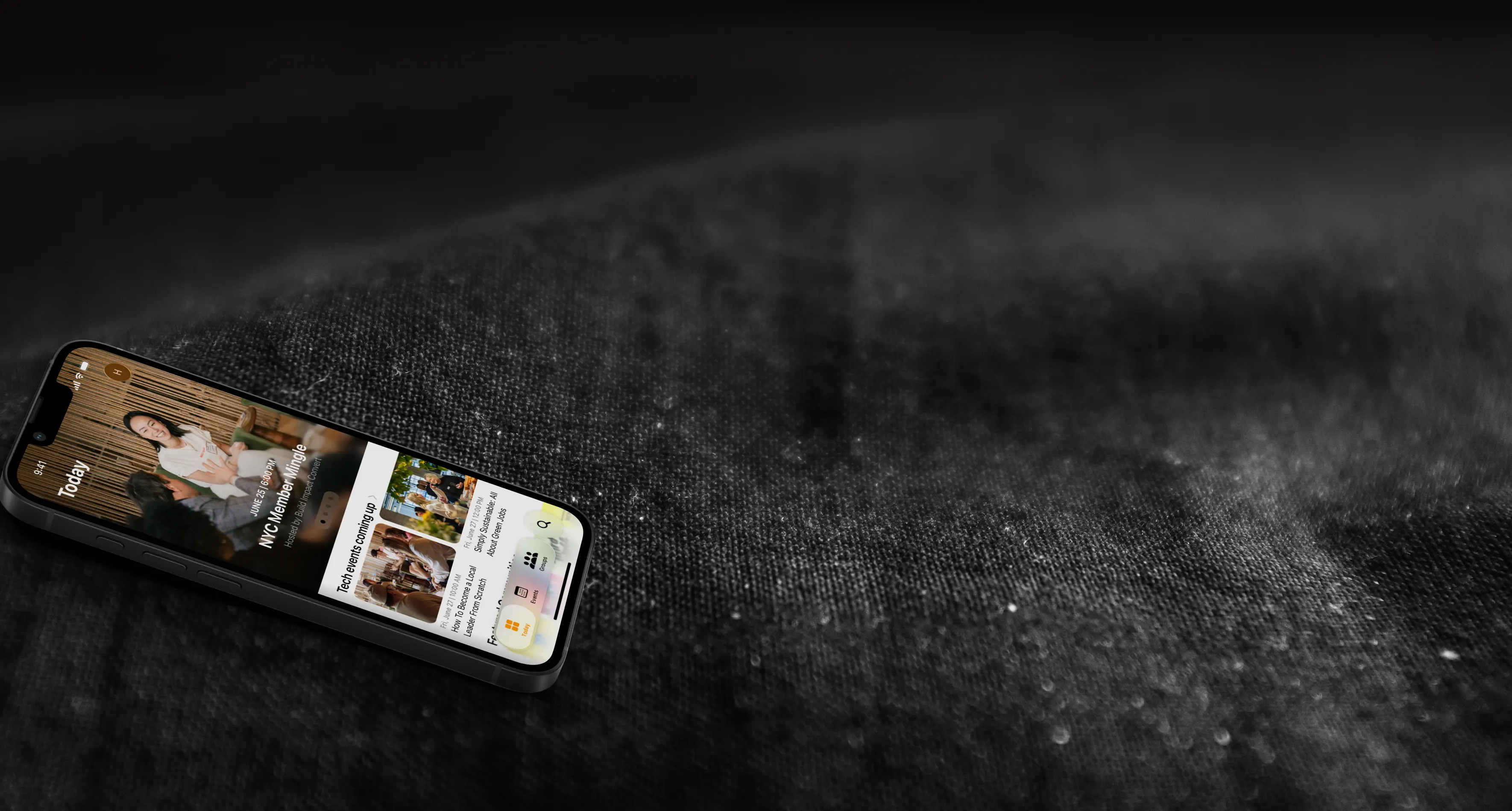 iPhone lying on dark woven fabric, showing the Fabrik Today feed of upcoming community events